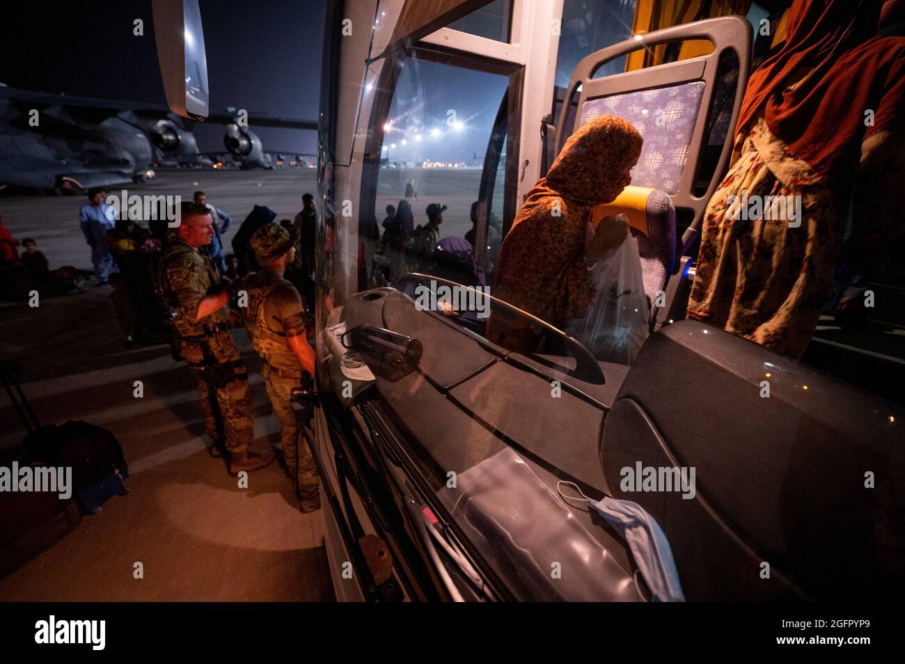 Al Udeied Air Base, Qatar. 23rd Aug, 2021. U.S. Air Force airmen assist Afghan refugees onto a bus to temporary housing on arrival from Kabul August 23, 2021 at Al Udeied Air Base, Qatar. Credit: Planetpix/Alamy Live News Stock Photo