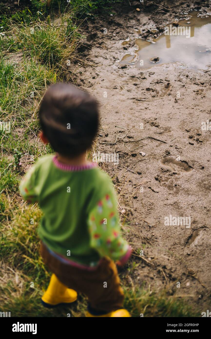 boy wearing rubber boots stands in front of puddle of mud Stock Photo ...