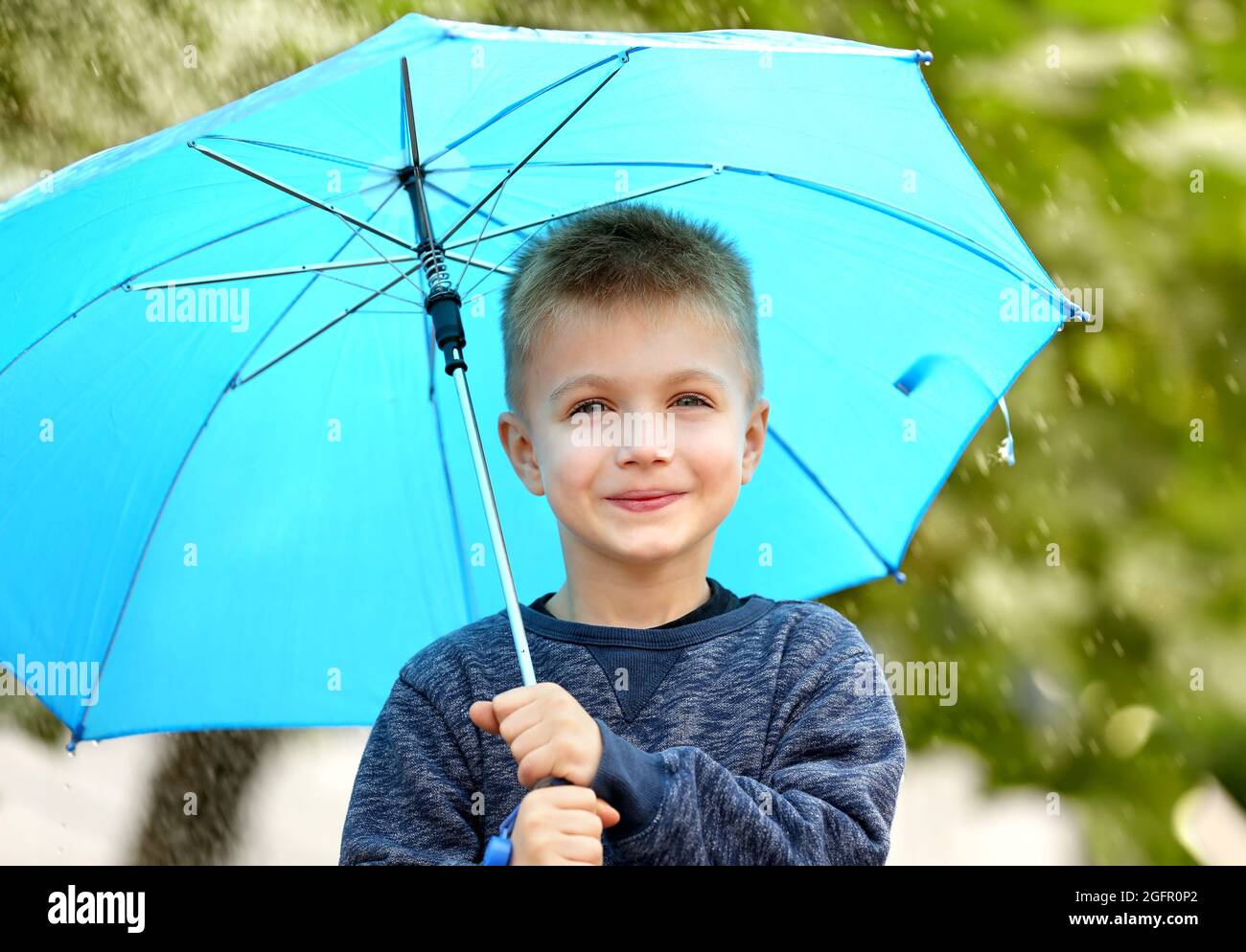 Portrait of boy with blue umbrella in rain Stock Photo Alamy