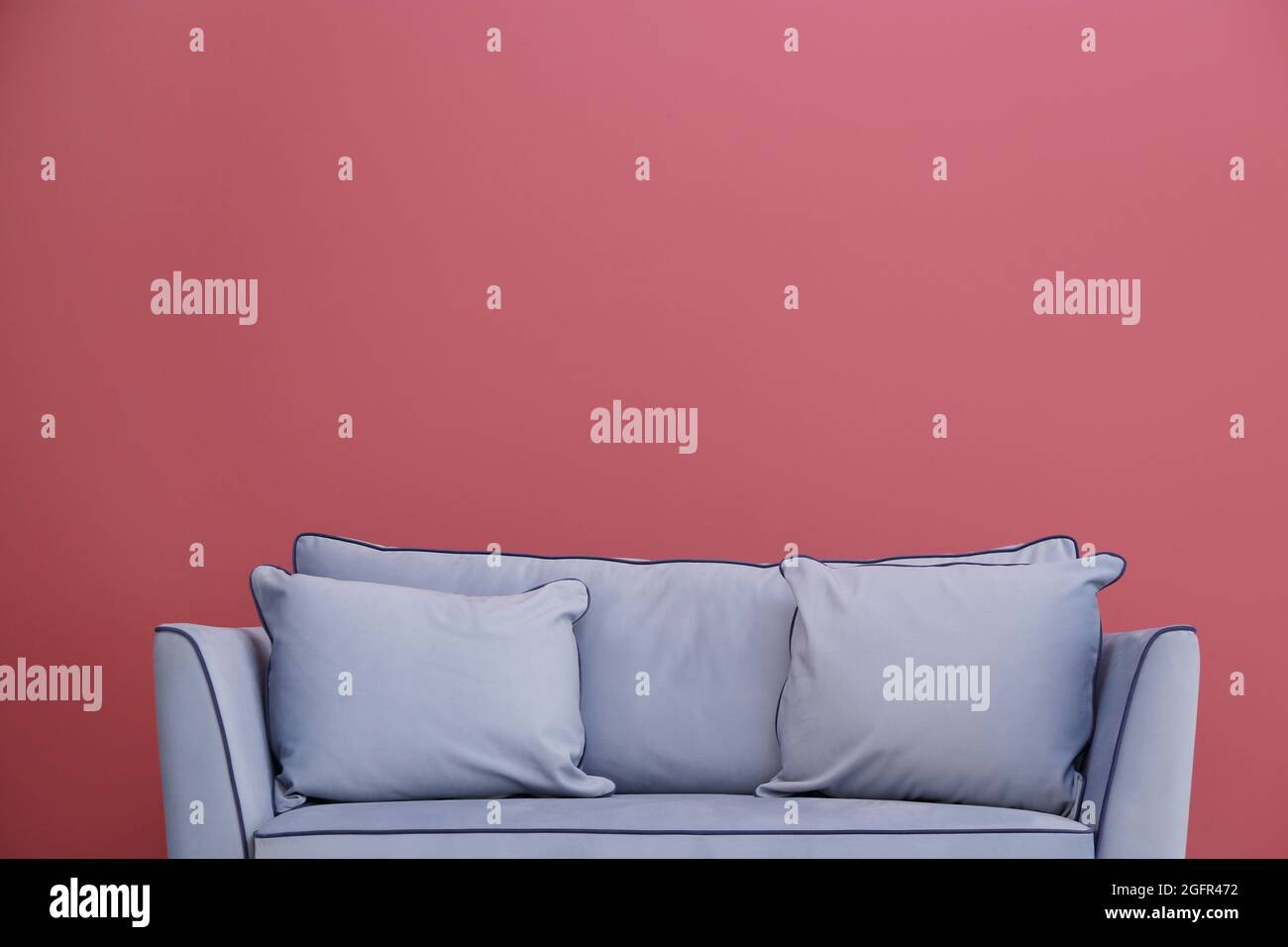 Modern couch on red wall background Stock Photo - Alamy