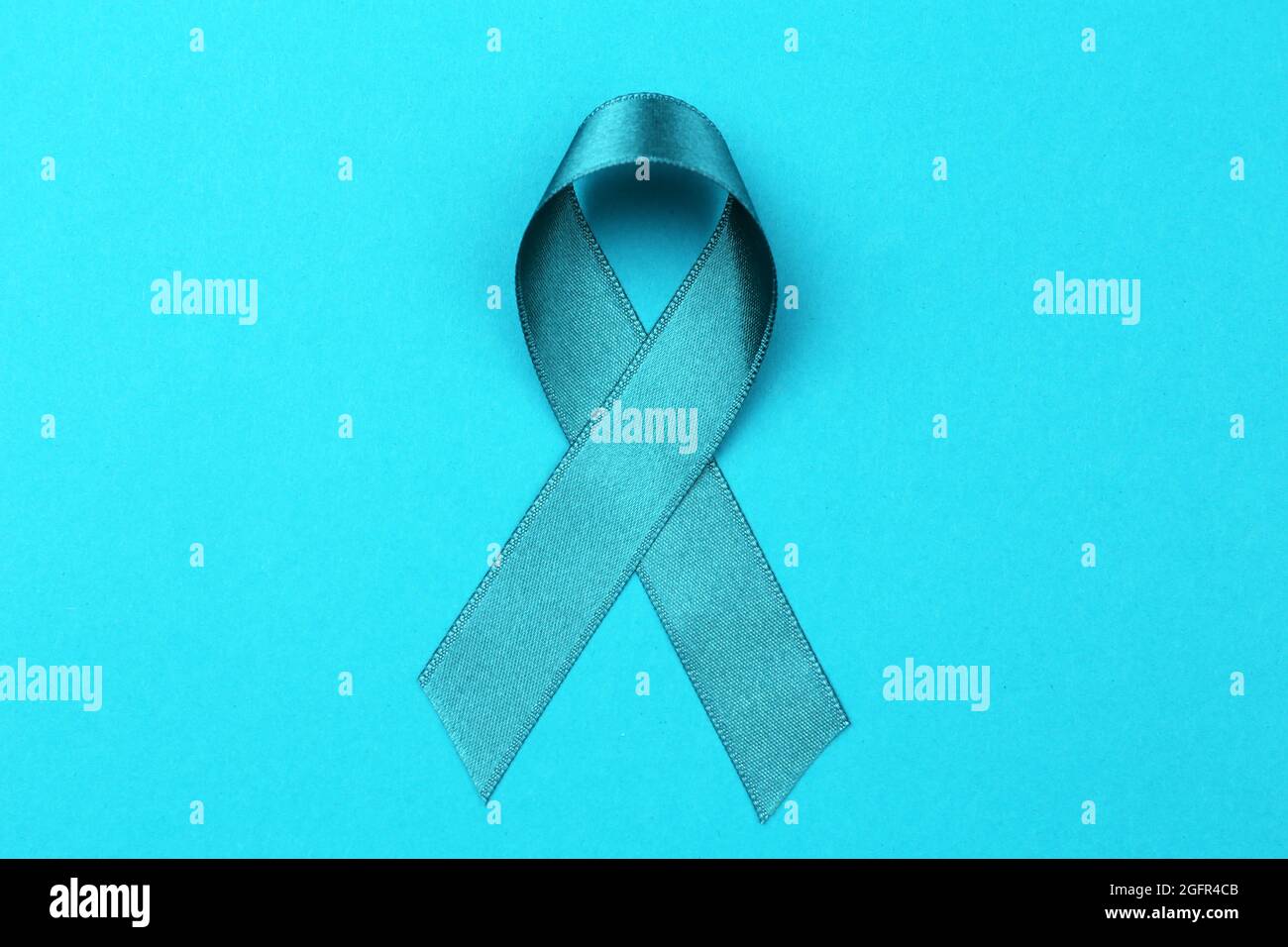 Seagreen ribbon on color background. Ovarian cancer and gynecological
