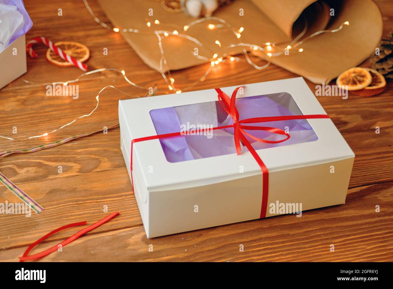 Christmas gift box with transparent lid on wooden table. Packaging