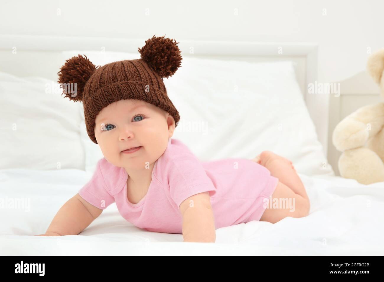 Cute baby wearing funny cap on bed Stock Photo Alamy