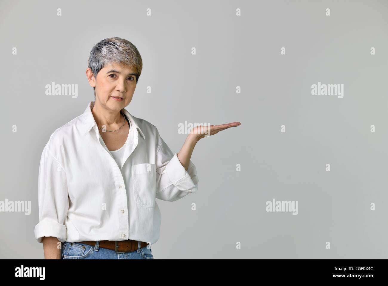Middle aged Asian woman showing empty copy space on the open hands palm ...