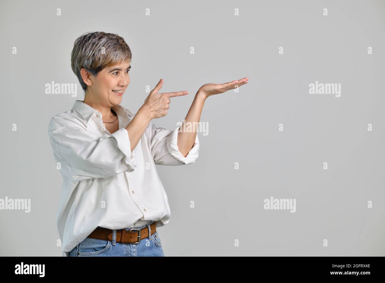 Middle aged Asian woman showing empty copy space on the open hands palm ...