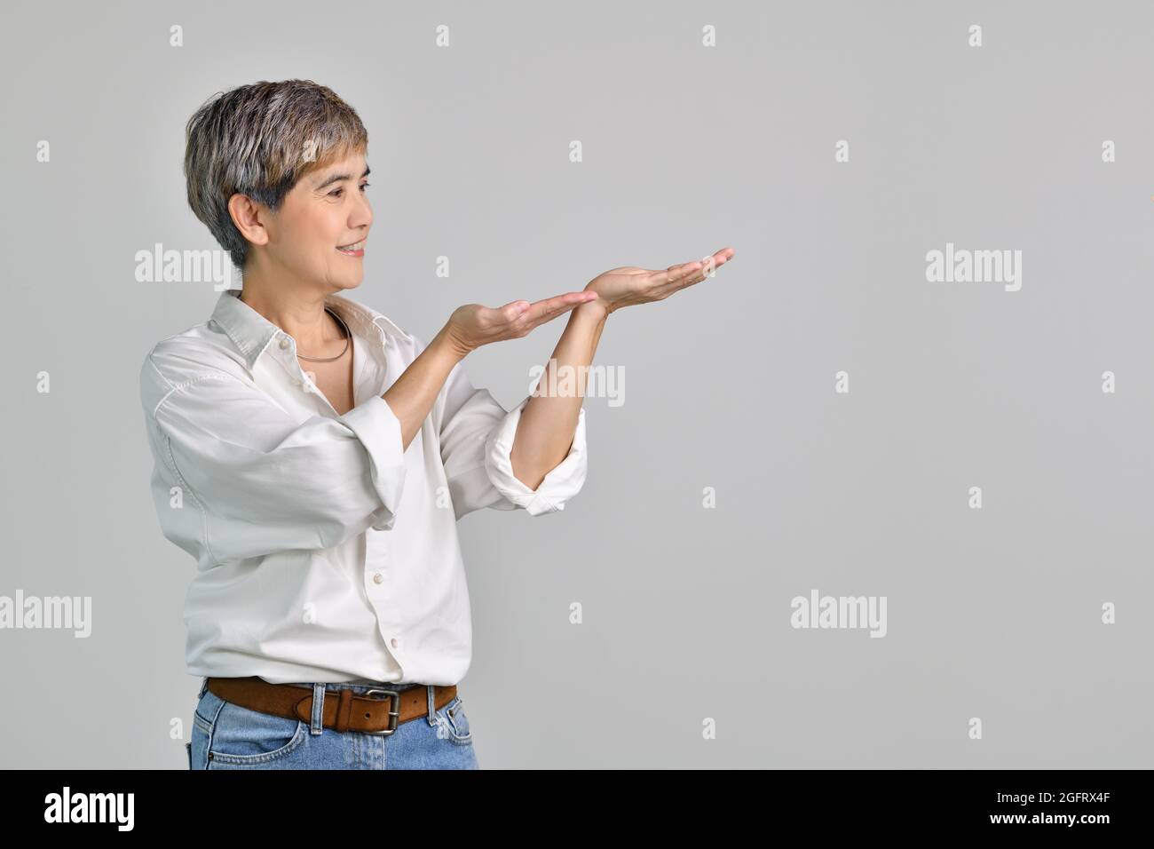 Middle aged Asian woman showing empty copy space on the open hands palm ...