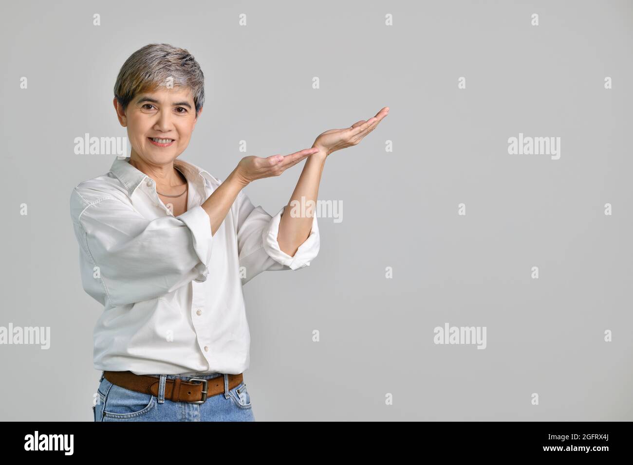 Middle aged Asian woman showing empty copy space on the open hands palm ...