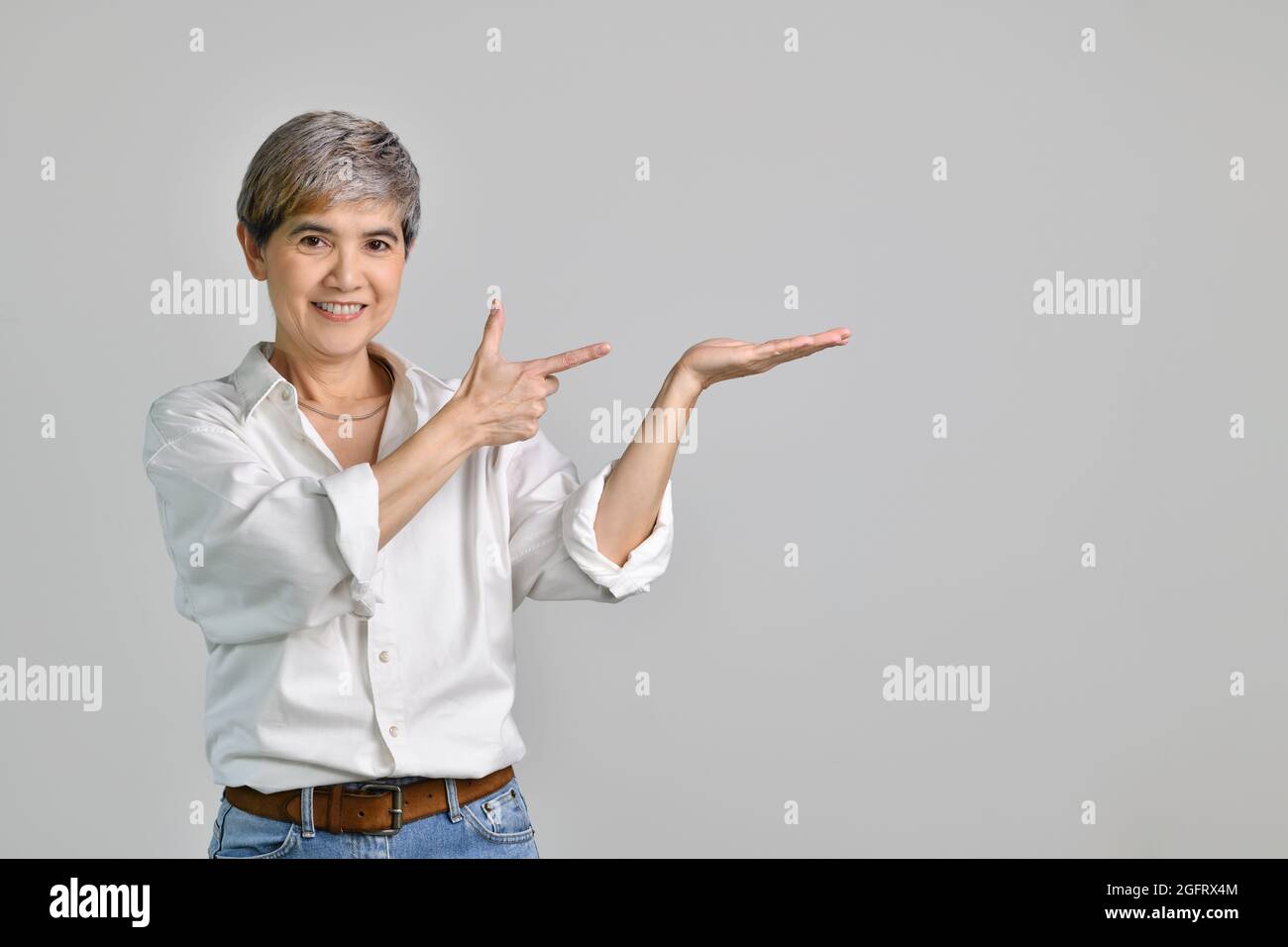 Middle aged Asian woman showing empty copy space on the open hands palm ...