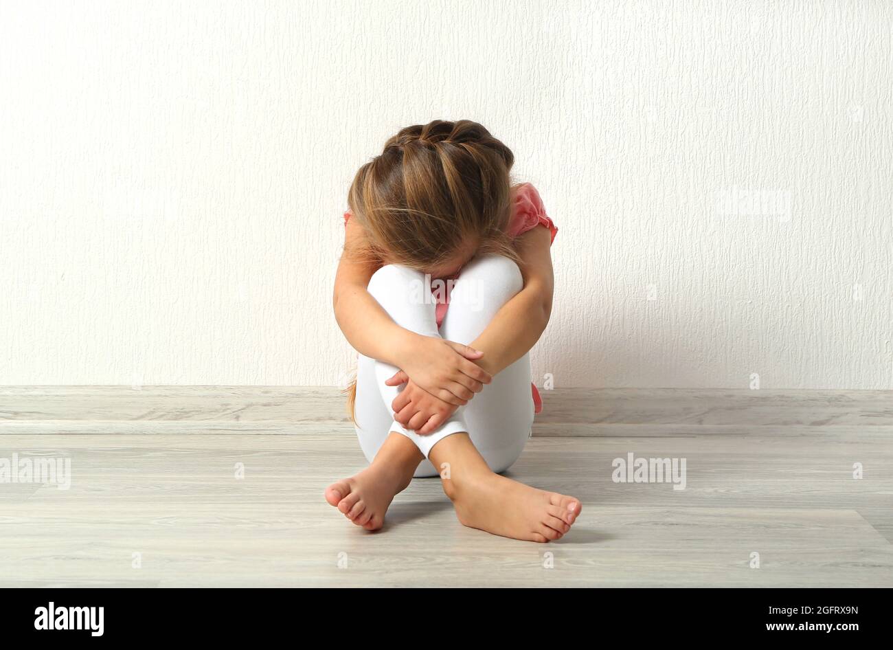Sad little girl sitting on floor in empty room Stock Photo - Alamy