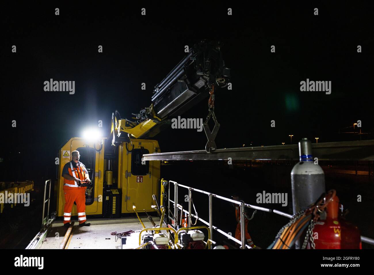 Hausach, Germany. 18th Aug, 2021. Mike Korell uses a crane to lift a rail section onto the track work vehicle (GAF). Deutsche Bahn is also renewing its track systems in remote regions of the country. A construction crew from Offenburg in Baden is on the road at night replacing rails. (to dpa summer series Baden-Württemberg by night : ''Don't make a mistake' - On a railway night construction site in the middle of the Black Forest') Credit: Philipp von Ditfurth/dpa/Alamy Live News Stock Photo