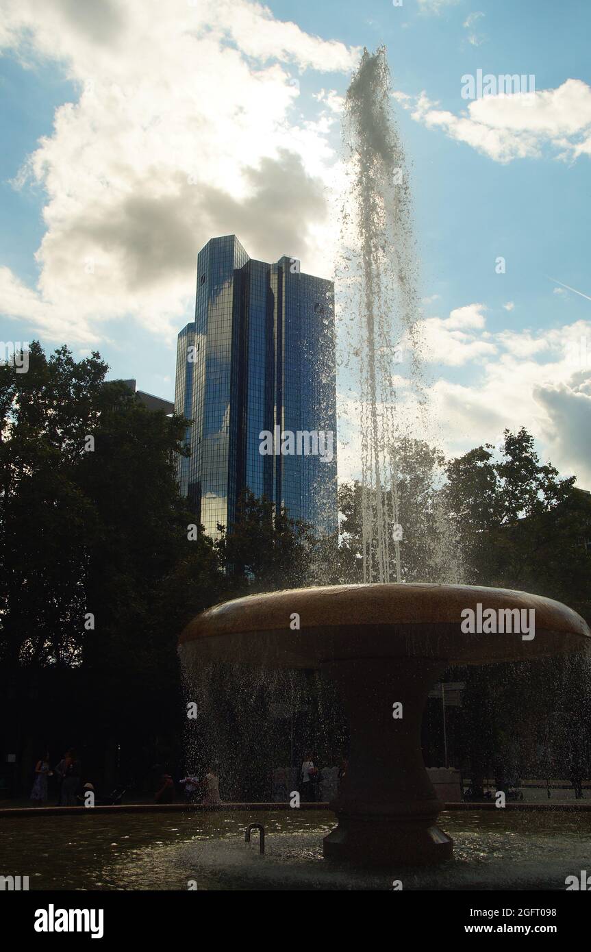 FRANKFURT, GERMANY - Aug 20, 2021: Backlight shot of the Lucae Fountain at Opernplatz with the Deutsche Bank Towers in the background in Frankfurt, Ge Stock Photo