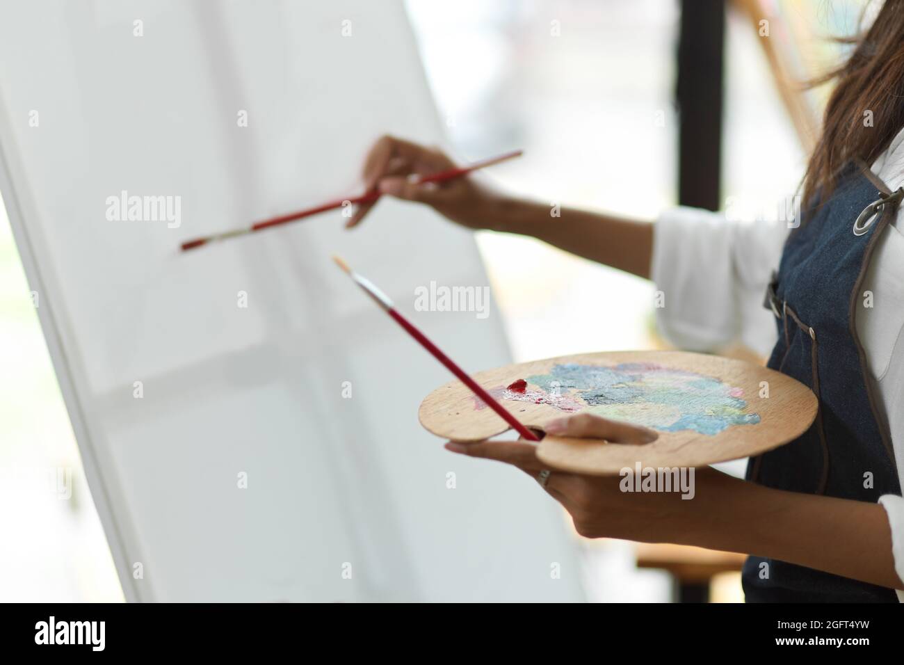 Cropped image, young female artist hold palette and paints on canvas by ...