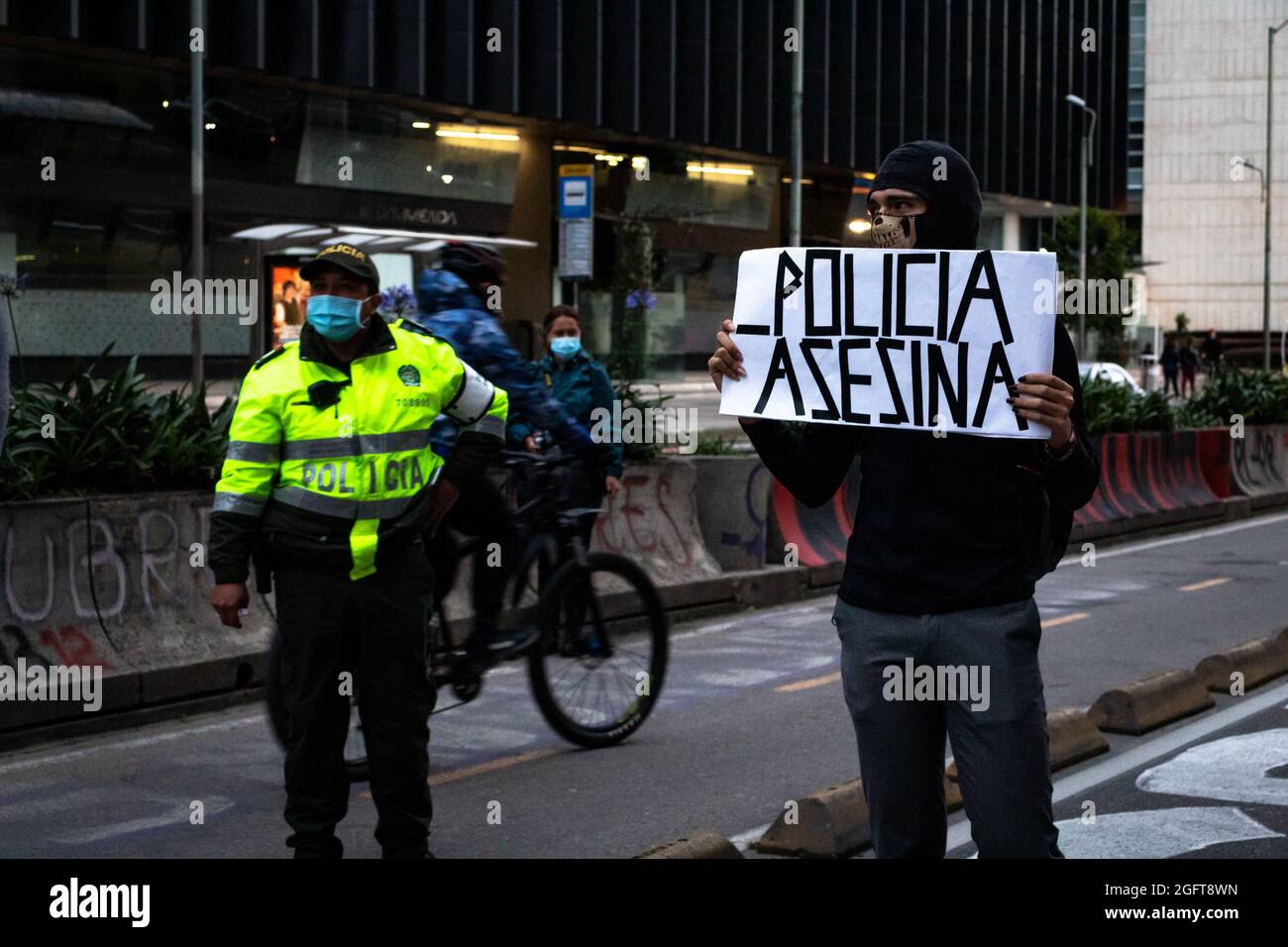 A demonstrator rises a banner that reads 'Killer Police' during a rally organized by students of the Universidad Distrital, after a few days back Esteban Mosquera, a social leader and community member was killed two years after loosing his eye on a police brutality case, in Bogota, Colombia on August 26, 2021. Stock Photo