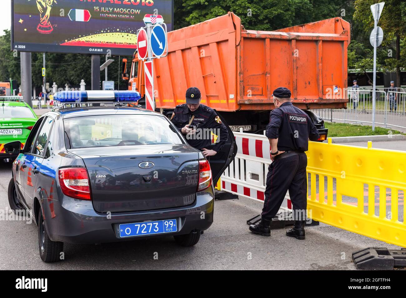 Employees of the non-departmental security of the Russian Guard standing next to the patrol car. For the convenience of football fans in Russian cities, places were organized for mass joint viewing of live broadcasts of football matches of the World Cup on huge screens. Anti-terrorist protection and the maintenance of public order in these places were provided by officers of the Russian Guard. Stock Photo