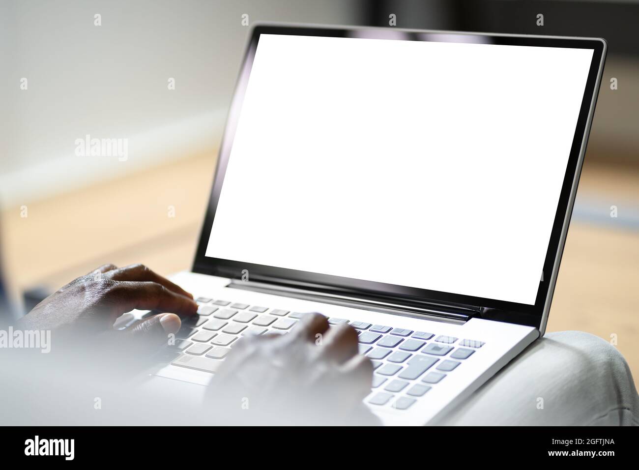 African Man On Couch Using Laptop With Empty Screen Stock Photo