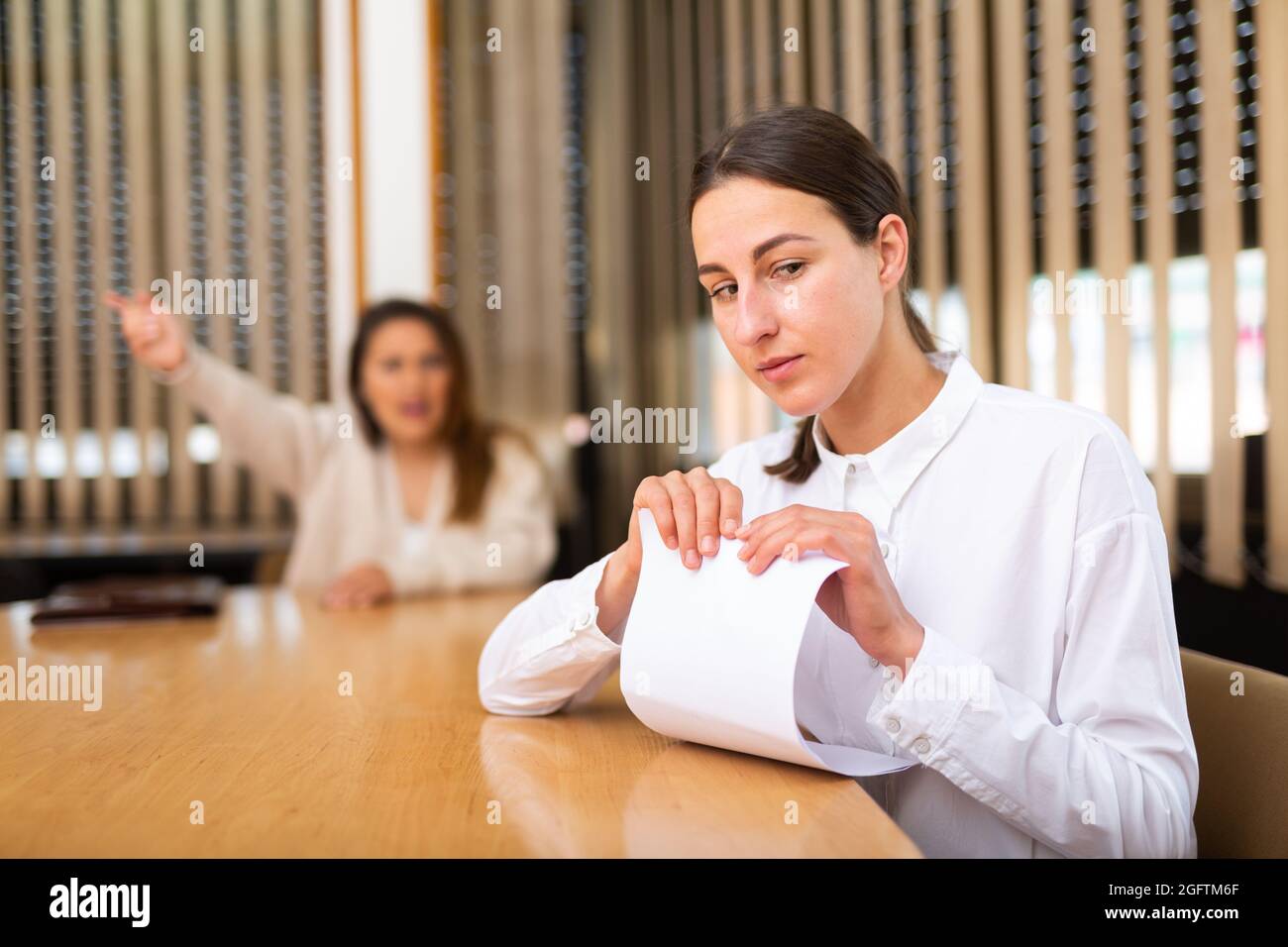 Unhappy female office employee after reprimand from angry chief Stock Photo