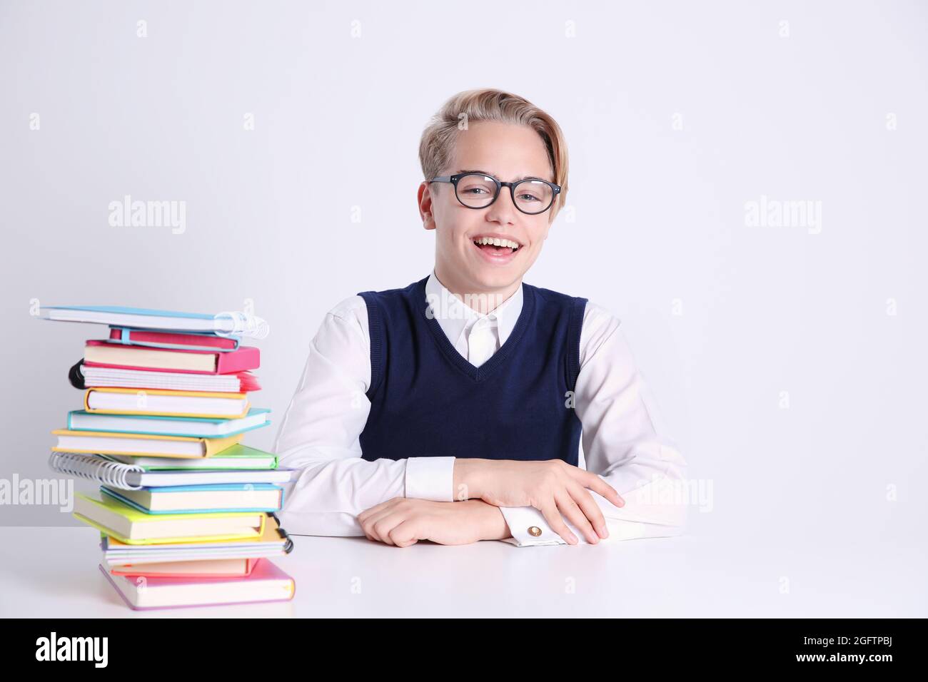 Pupil with pile of books sitting at table on white background Stock ...