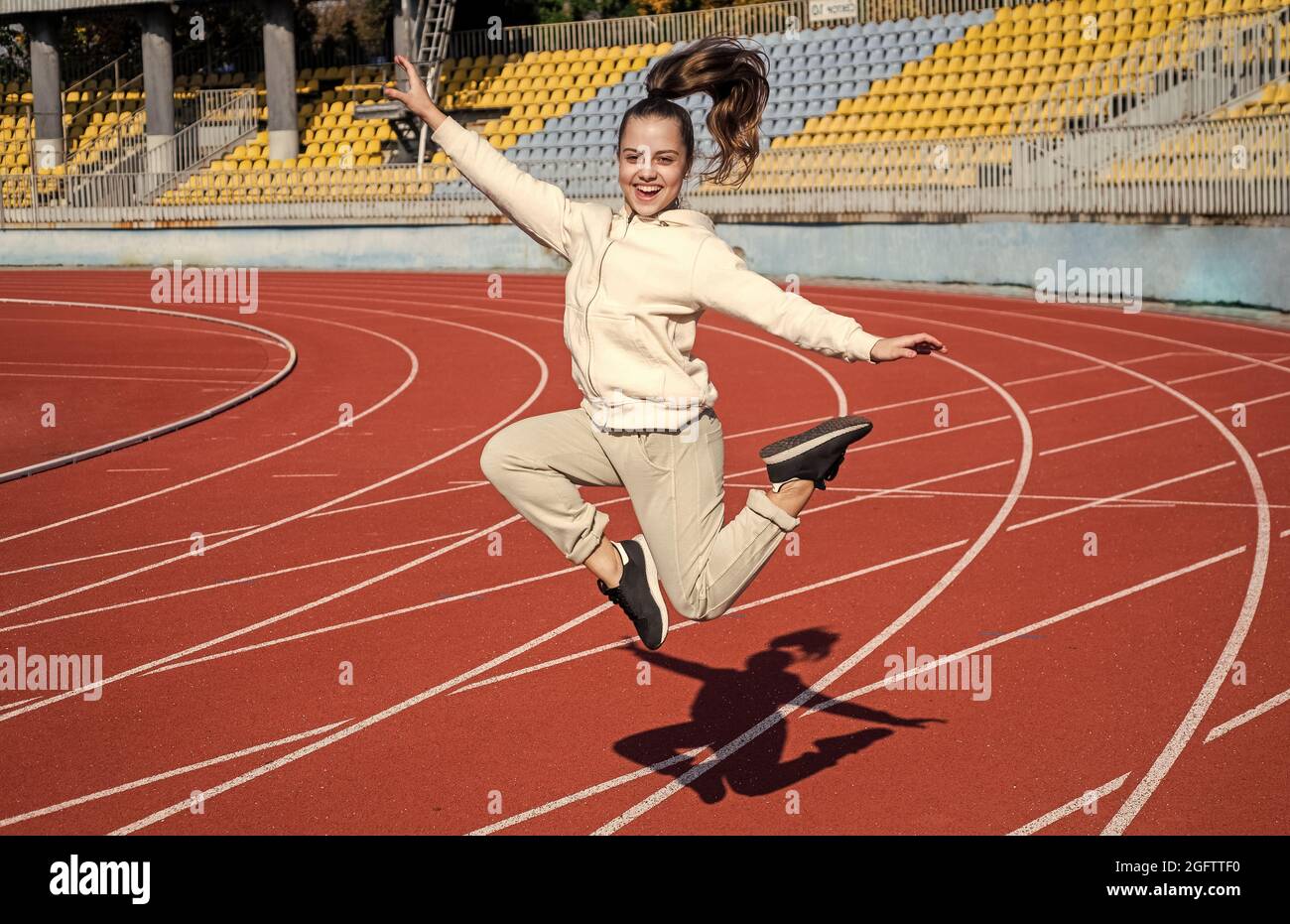 Energetic girl child jump at athletics track physical education