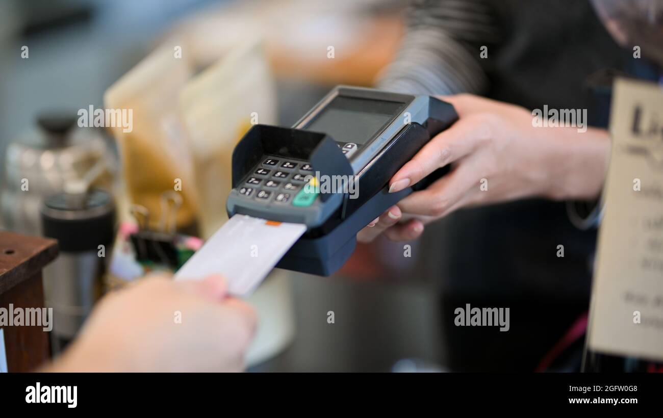 Closeup image of customer insert credit card in payment machine to pay coffee drink at coffee