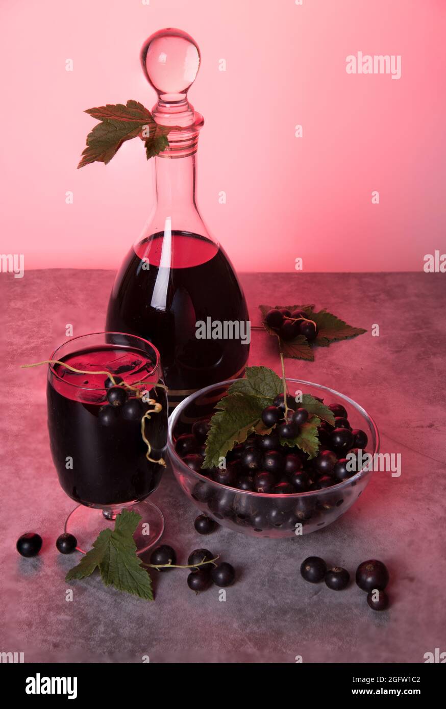 Black currant berries and homemade liqueur in a glass and decanter. Low ...