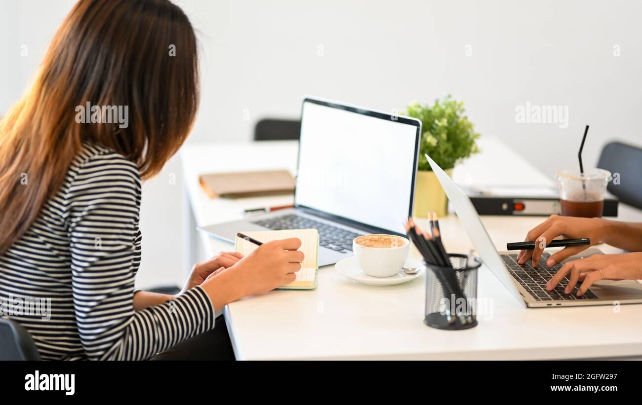 Female secretary checking mail on laptop, organising work, taking notes, laptop mockup, businesswoman working at office Stock Photo