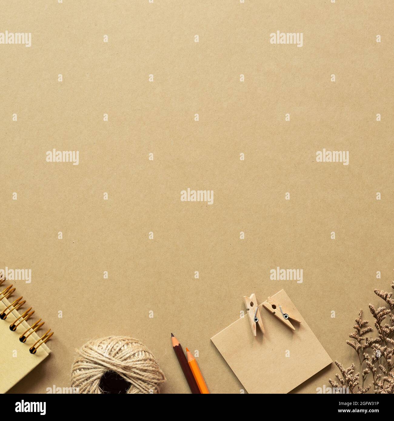 Notebook, twine, colored pencil, notepad, wooden clip, dry flower on brown background. workspace. top view, copy space Stock Photo