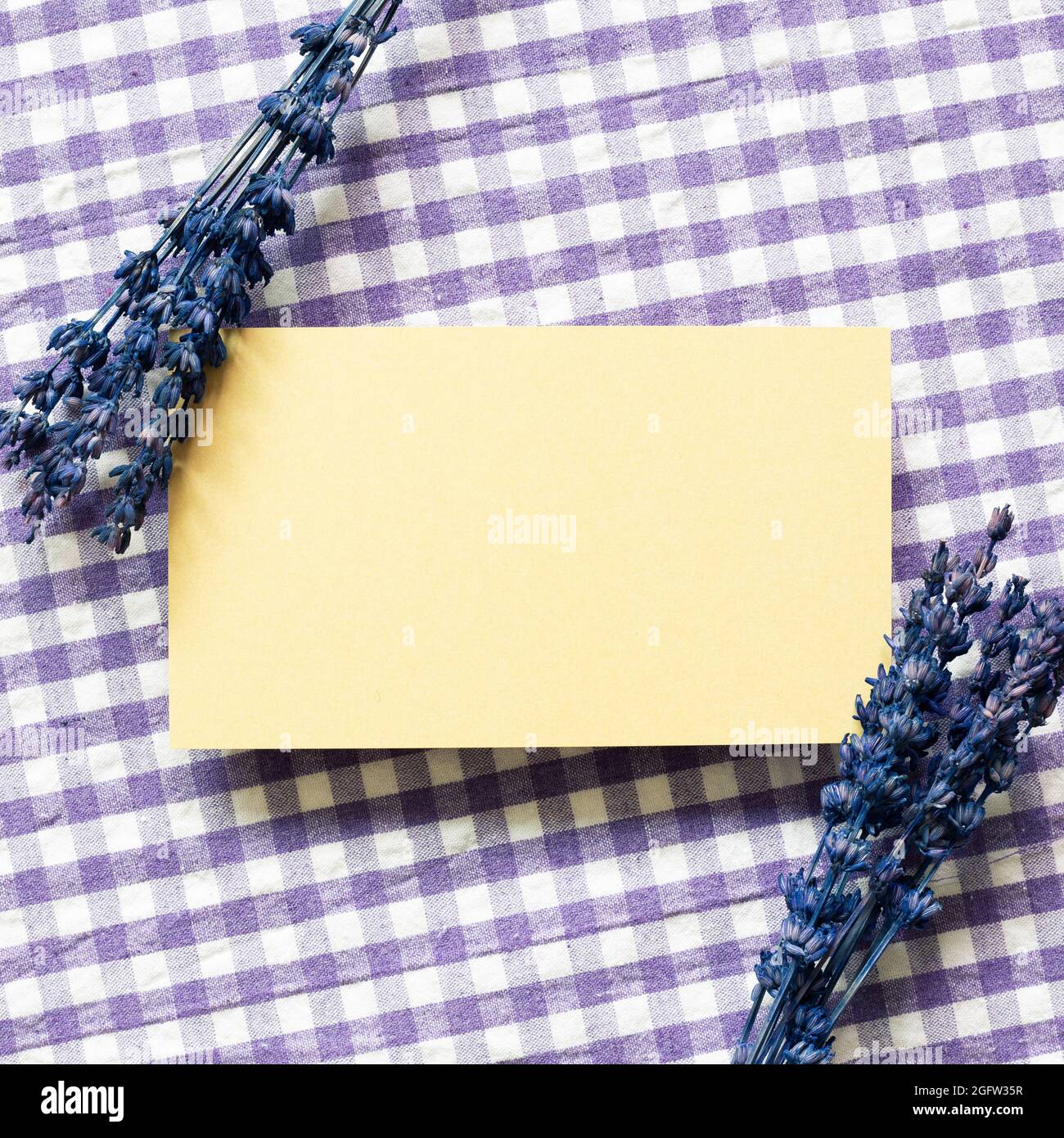 Yellow memo pad with purple lavender flowers on check pattern fabric background. top view, copy space Stock Photo