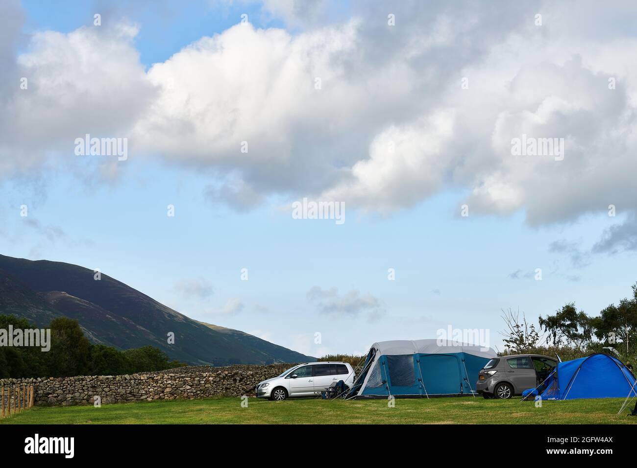 Tent camping on a farm field in the Lake District opposite the Blencathra (Saddleback) fell on a cloudy, misty summer day. Stock Photo