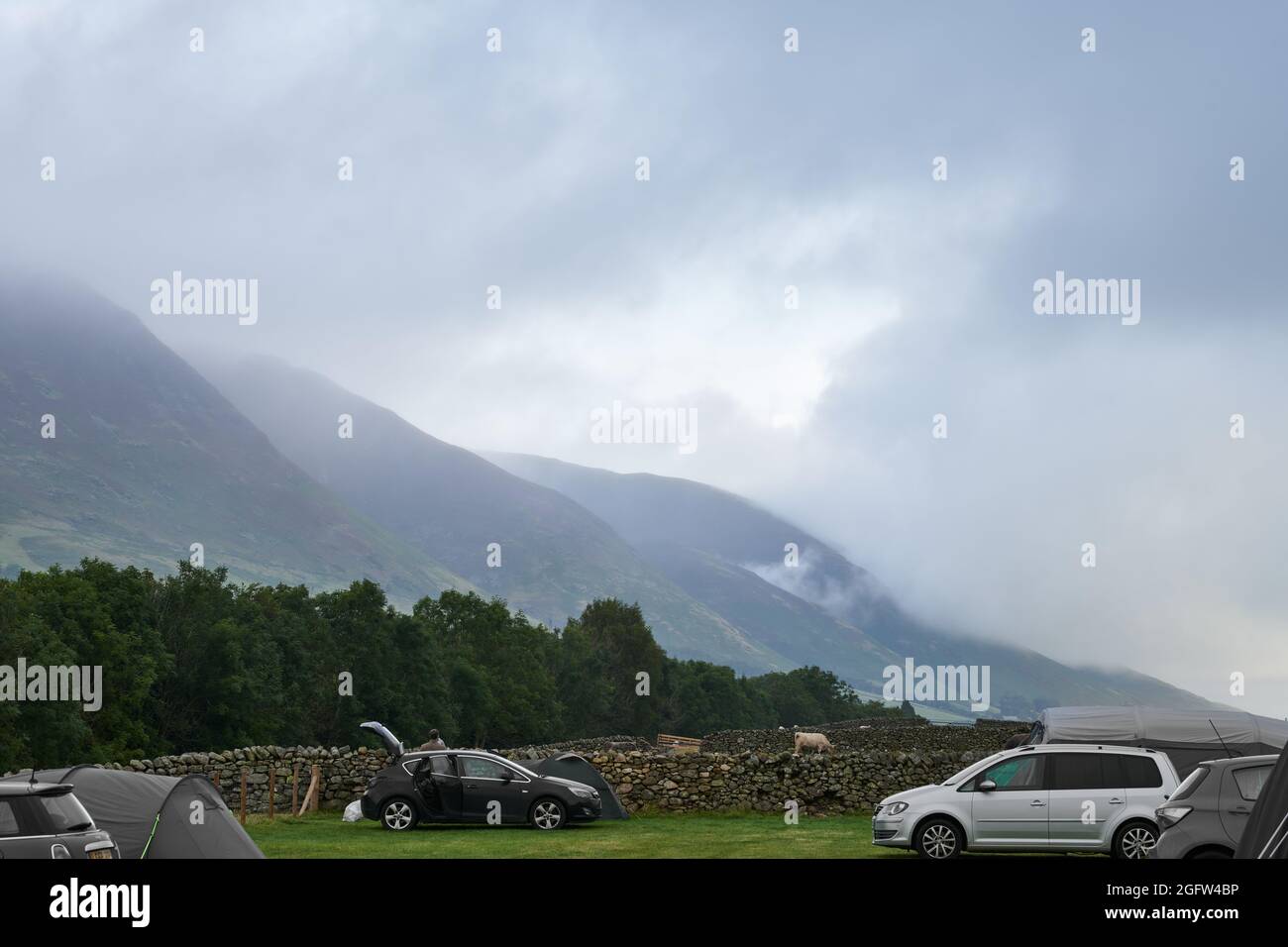 Tent camping on a farm field in the Lake District opposite the Blencathra (Saddleback) fell on a cloudy, misty summer day. Stock Photo