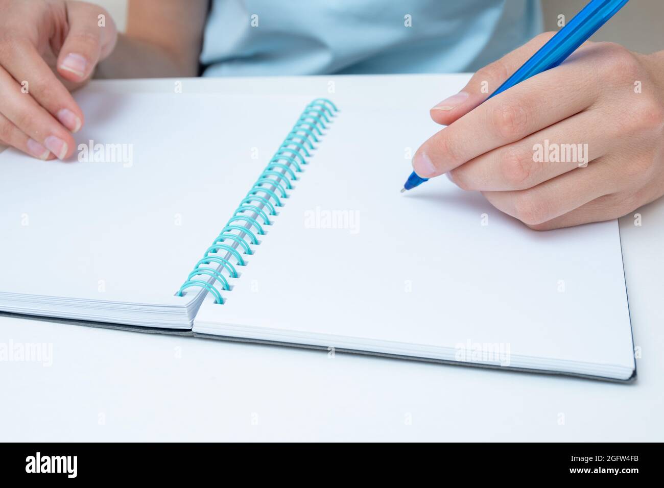 Female student hand holding a pen writing in a notebook, large poan ...