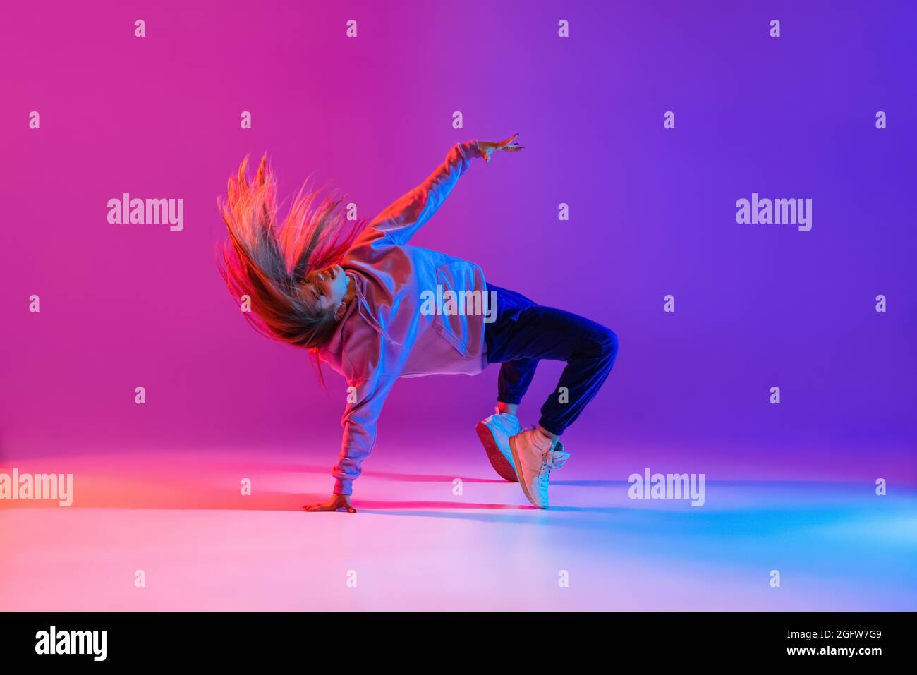 Attractive active young girl dancing and showing hip-hop tricks isolated on  gradient pink purple neon studio background Stock Photo - Alamy