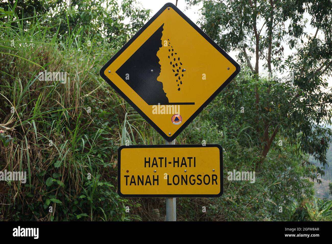 Yellow sign with a natural background. Hati-hati tanah longsor means beware of landslides Stock Photo