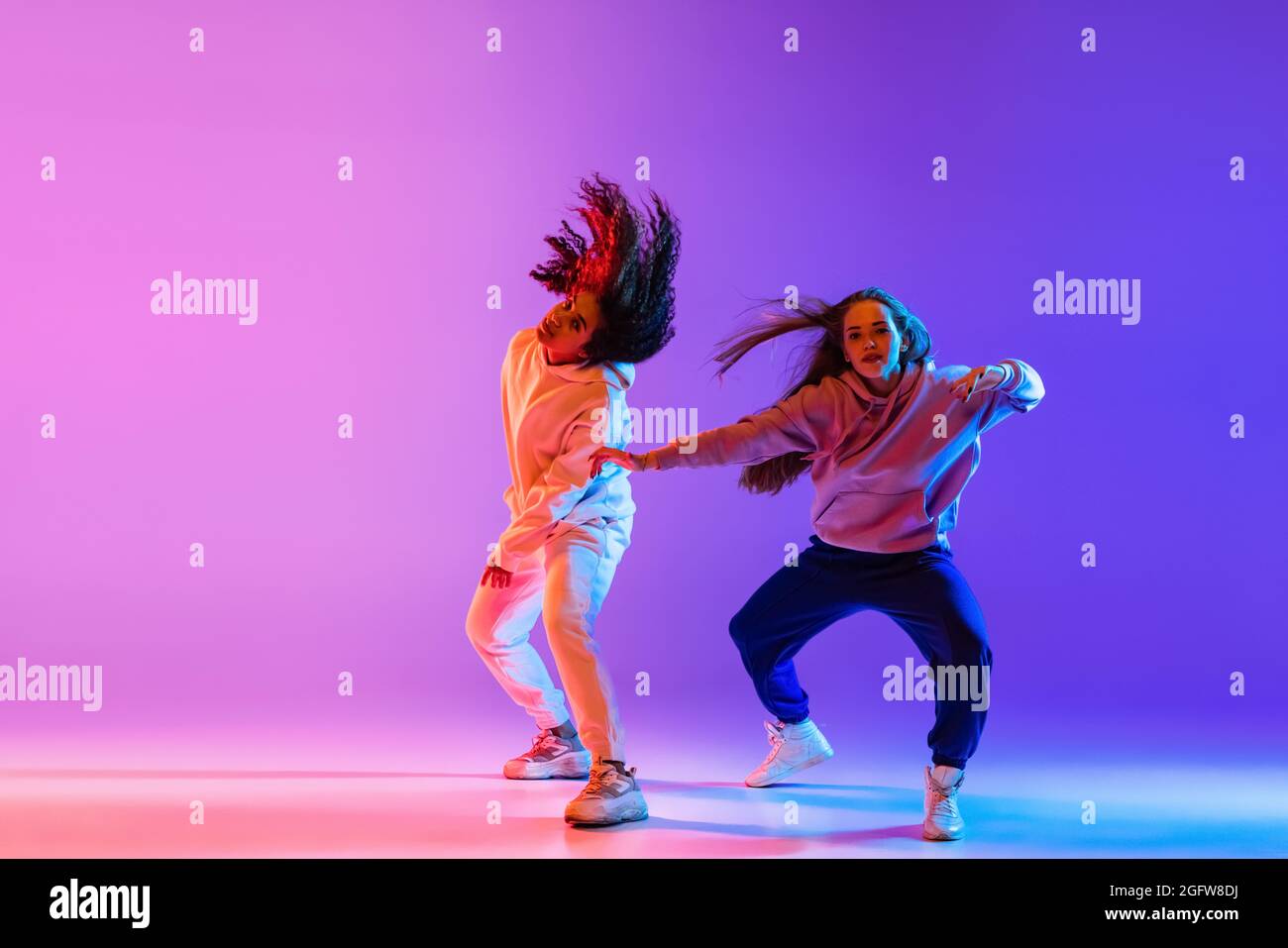 Two beautiful young girls dancing hip-hop in stylish clothes on ...