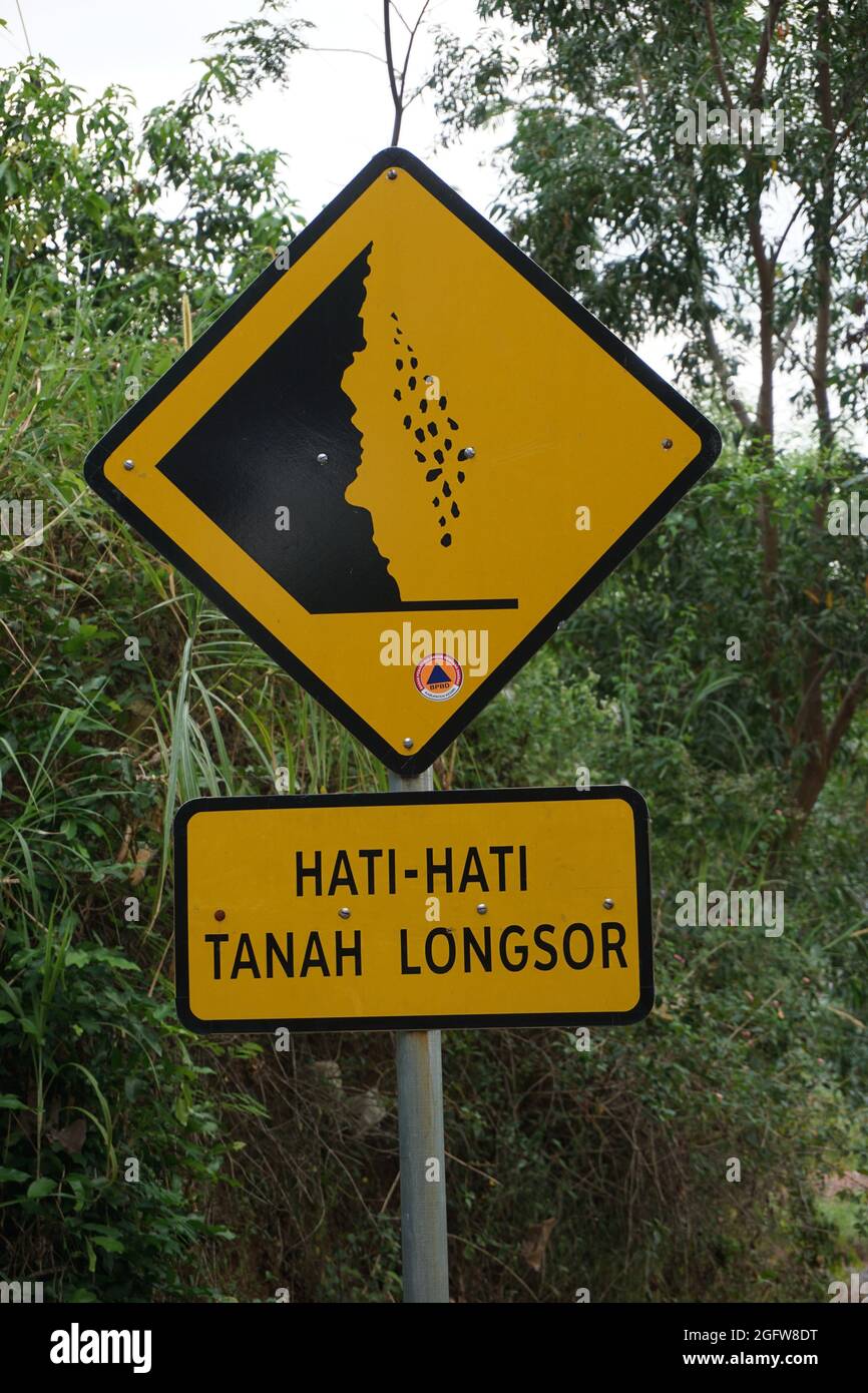 Yellow sign with a natural background. Hati-hati tanah longsor means ...