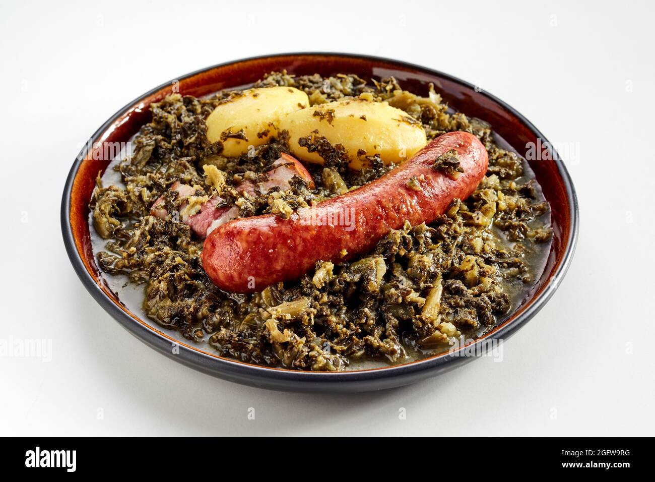 Traditional German dish of spicy sausage and braised fresh kale rich in nutrients served on a plate with two baby potatoes in a close up high angle vi Stock Photo