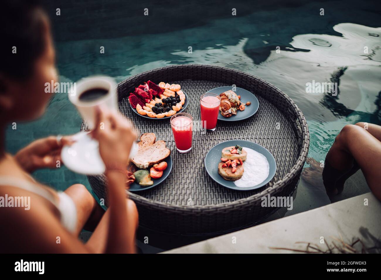 Girl relaxing and eating fruits in the pool on luxury villa in Bali