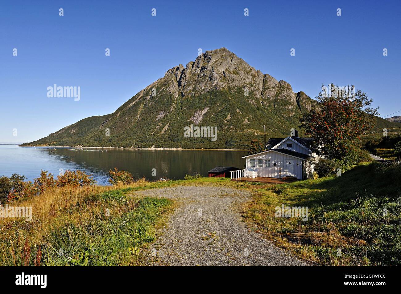 House at Lia on the Aldra Sound, with the peak of Okstind behind, Norway, Haugland, Aldra Island Stock Photo
