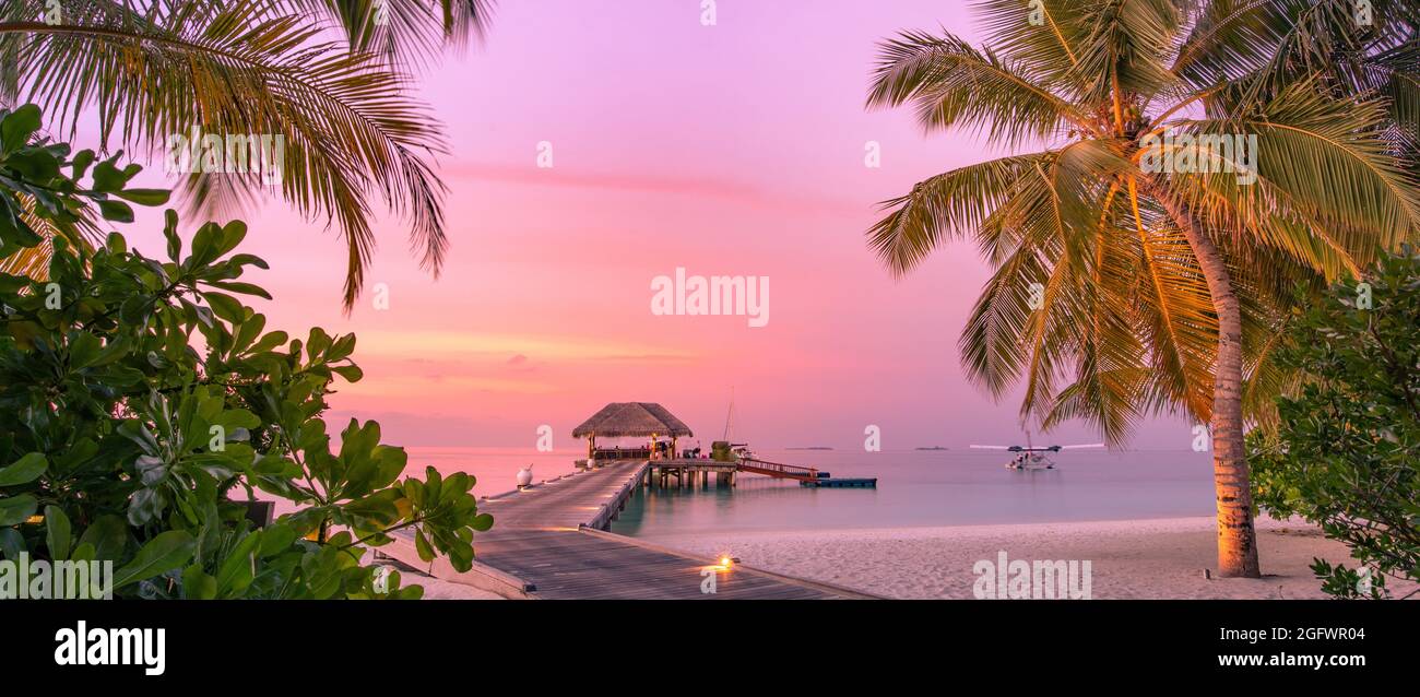 Amazing beach panoramic landscape. Beautiful Maldives sunset seascape view. Horizon colorful sea sky clouds, over water villa pier pathway. Tranquil Stock Photo