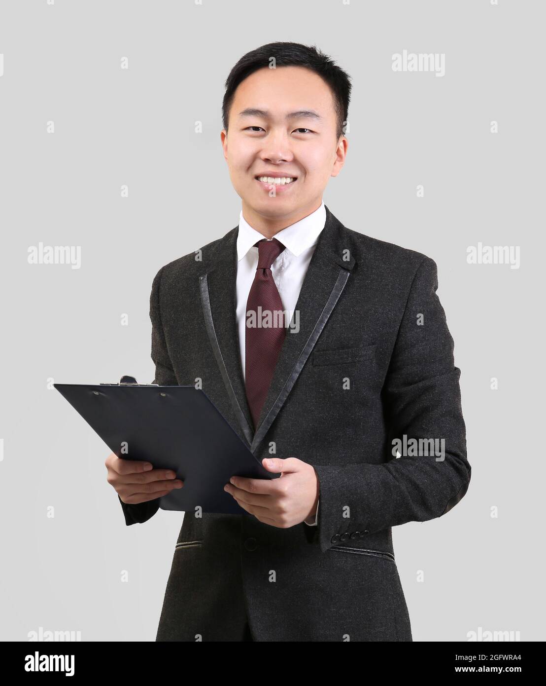 Handsome Asian man with clipboard on light background Stock Photo - Alamy