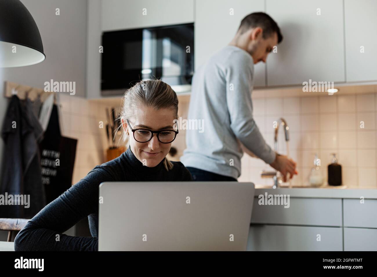 Woman in kitchen using laptop Stock Photo