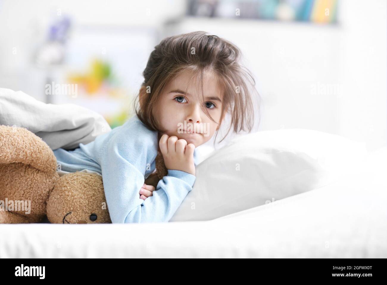 Cute little girl lying in bed with cuddly toy Stock Photo Alamy