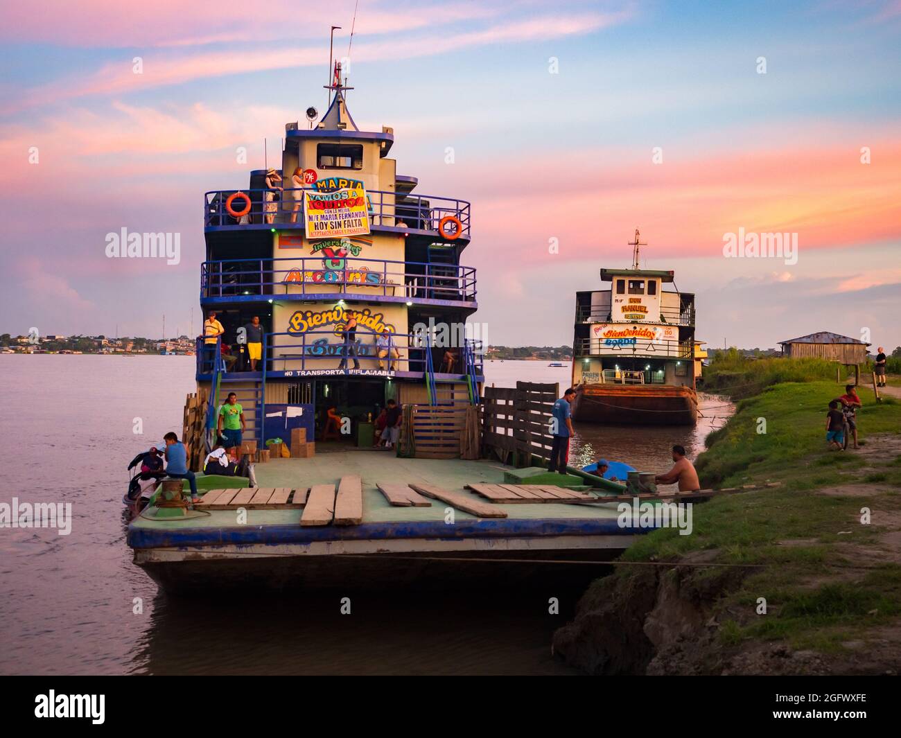 Santa Rosa, Peru - Mar 24, 2018: Sunrise over the Amazon river and the cargo boat waiting at the port. Stock Photo