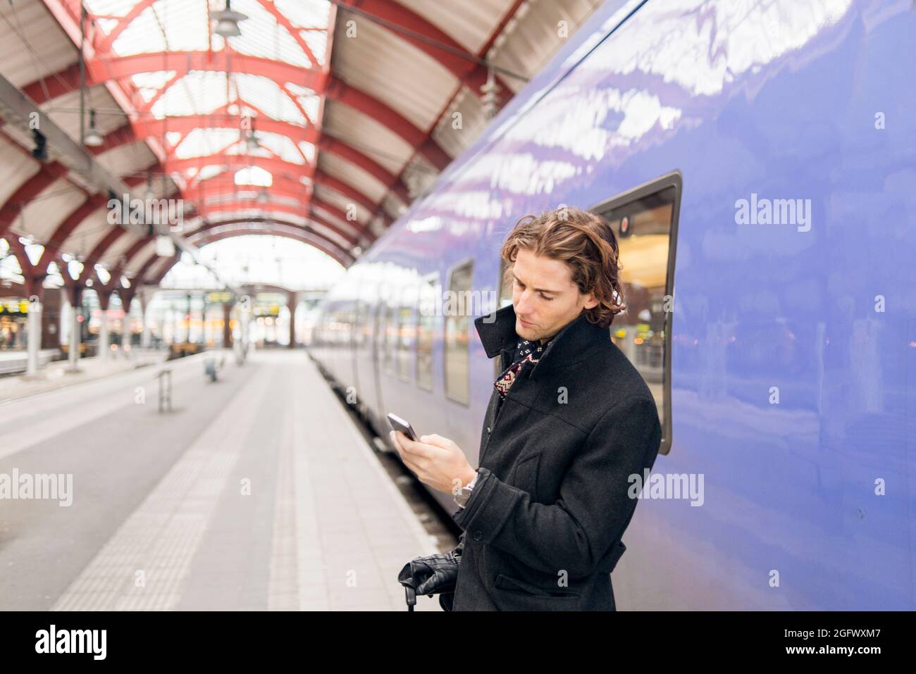 Man using phone at train station Stock Photo
