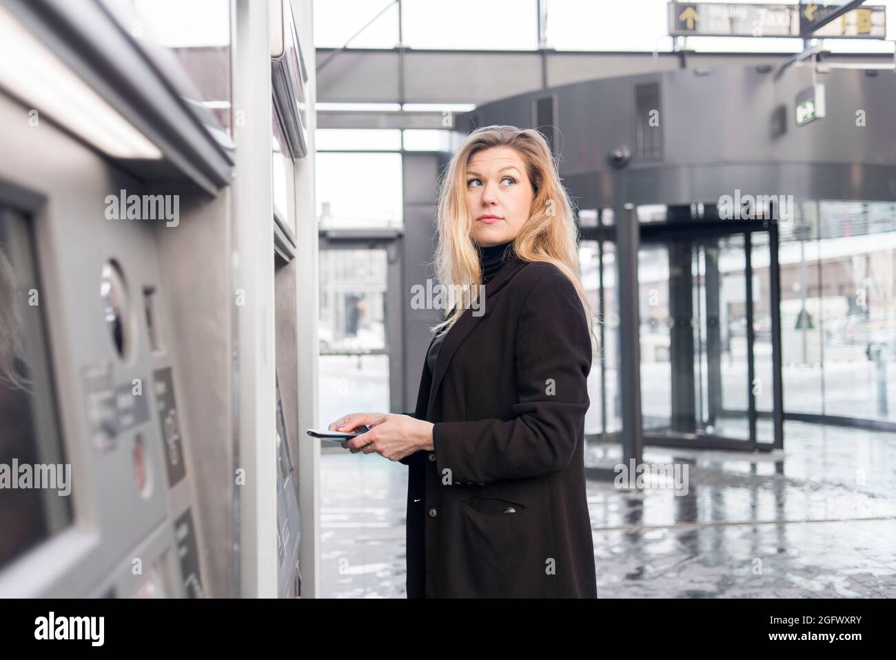 Woman using ticket machine at train station Stock Photo - Alamy