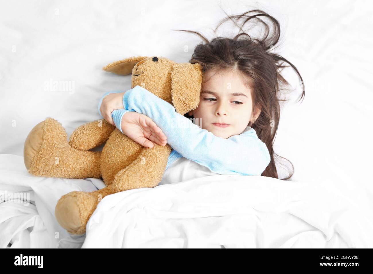 Cute little girl lying in bed with cuddly toy Stock Photo - Alamy