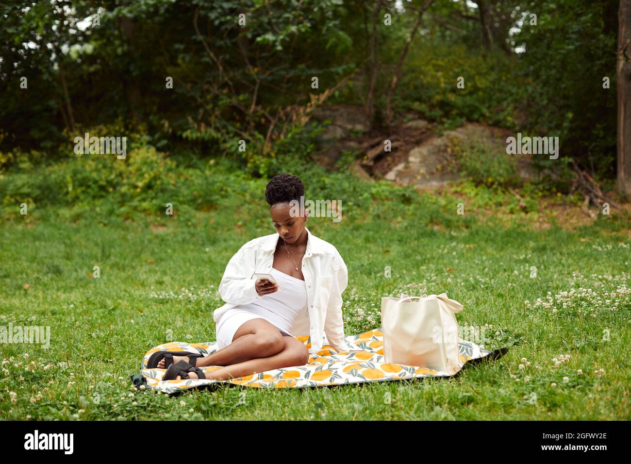 Woman sitting on blanket in park Stock Photo