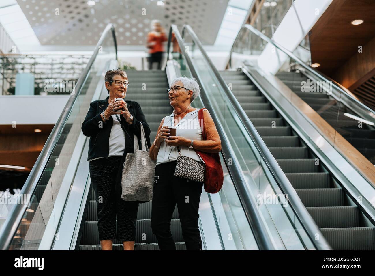 Senior women standing on escalator Stock Photo