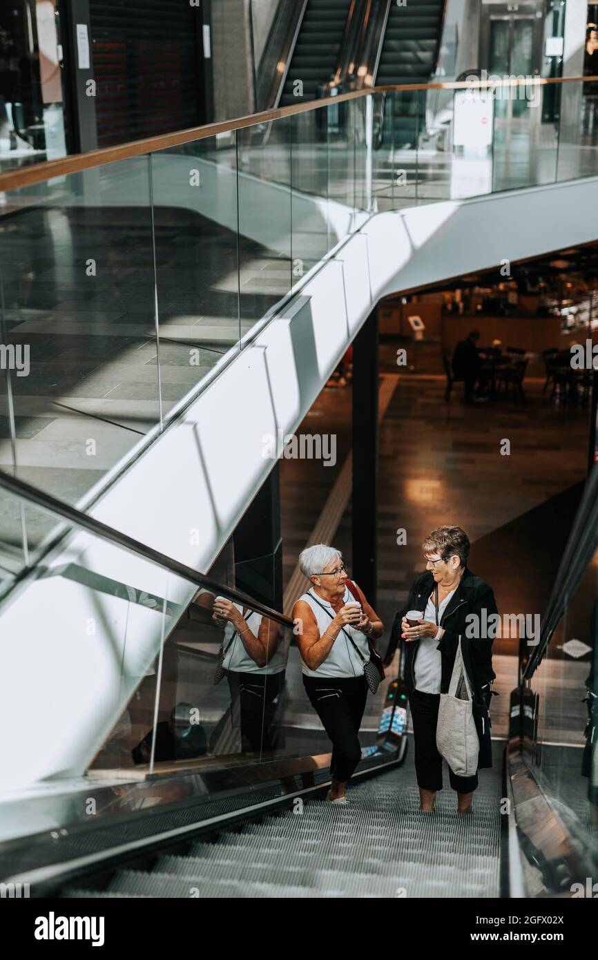 Senior women standing on escalator Stock Photo