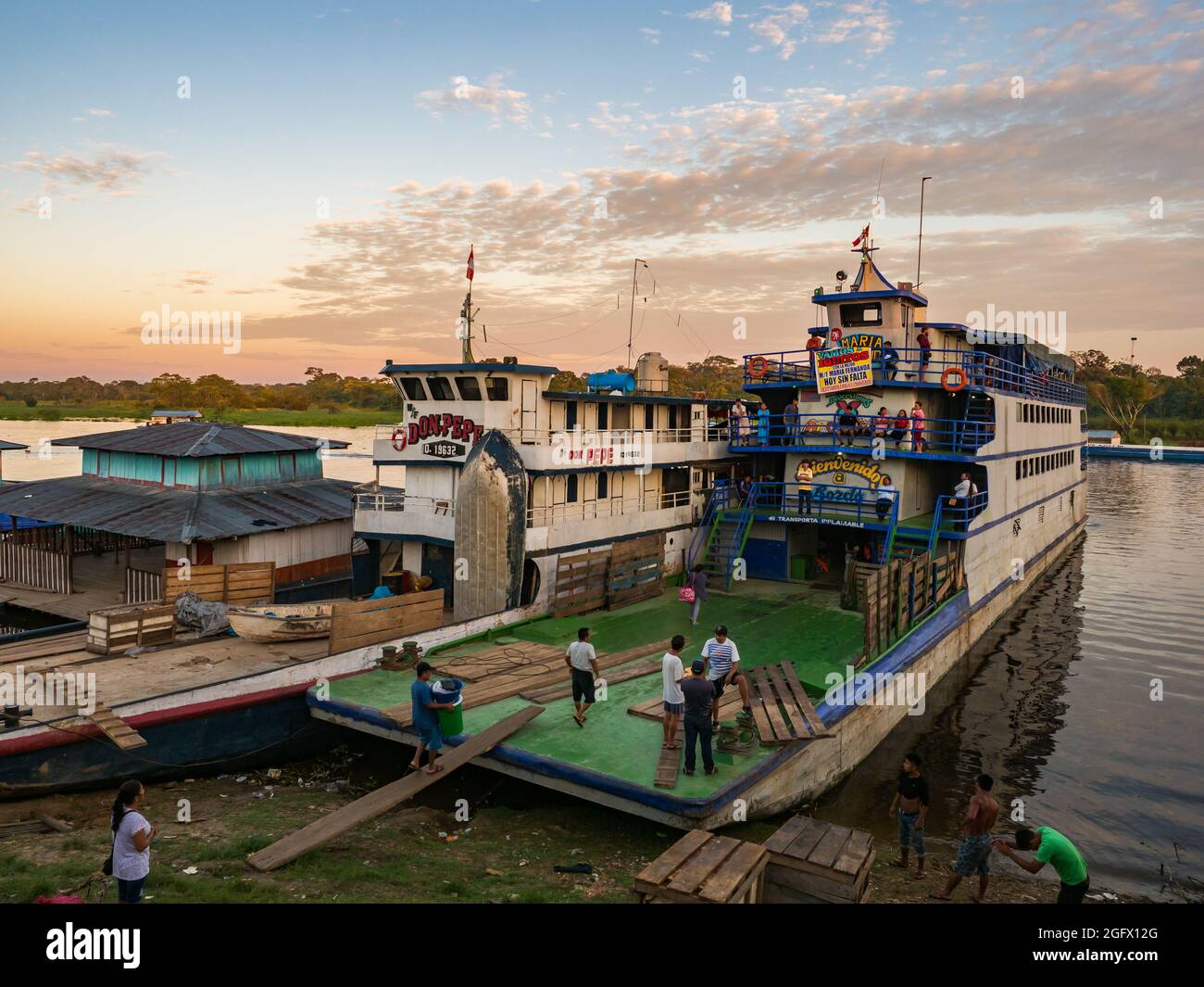 Santa Rosa, Peru - Mar 24, 2018: Sunrise over the Amazon river and the cargo boat waiting at the port. Stock Photo