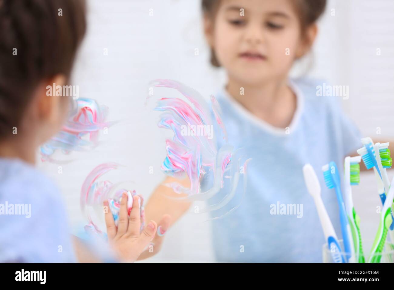 Little girl smearing toothpaste on mirror in bathroom Stock Photo Alamy